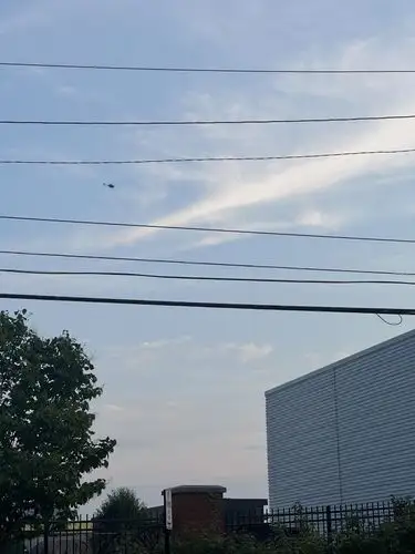 Urban sky meets power lines and distant flight.